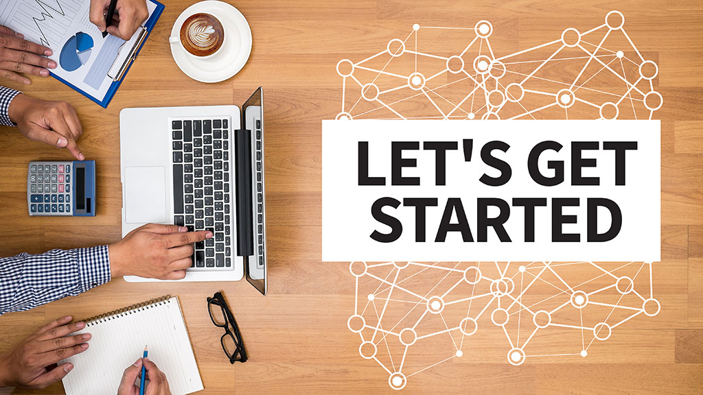 A desktop with a laptop and coffee, and a sign saying "Let's Get Started"